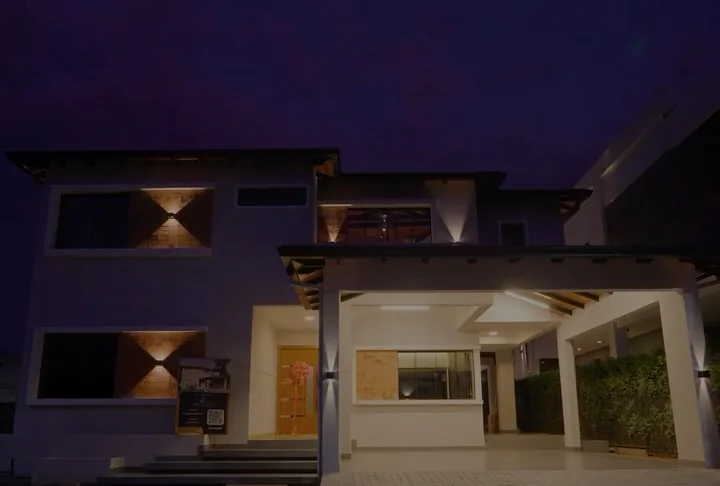 Vivienda de dos plantas terminada, de noche, con las luces de fachada encendidas